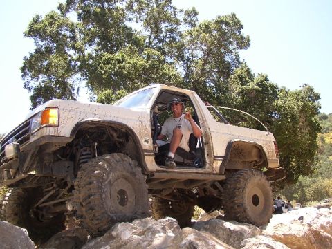 1989 Ford Bronco - This heavily modified SUV navigates a rocky trail with its driver giving a peace sign.