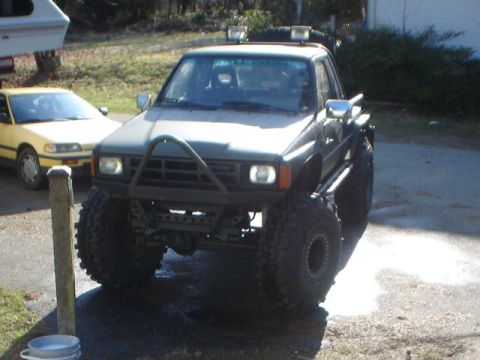 1990 Ford Bronco - A heavily modified truck with oversized tires and auxiliary lights sits in a driveway.