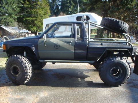 1990 Ford Bronco - This heavily modified pickup truck features oversized tires, a custom roll cage, and a spare tire rack, suggesting it's built for extreme o…