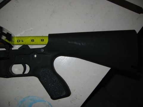 1996 Ford Bronco - A yellow measuring tape is placed against a black gun receiver, indicating its length.