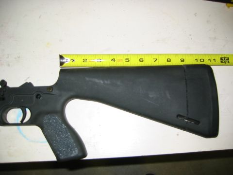 1996 Ford Bronco - A black gun stock and receiver is measured with a yellow tape measure.