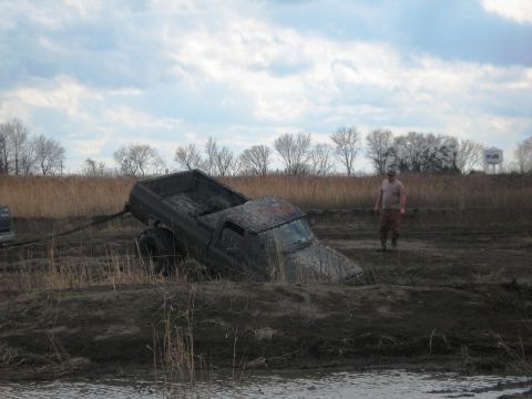 1990 Ford Bronco - A mud-covered pickup truck is stuck in a muddy field, with a person observing the scene.