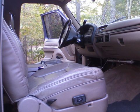 1996 Ford Bronco - The interior of a 1996 Ford Bronco is shown with the driver's side door open, revealing the tan leather seats and dashboard.