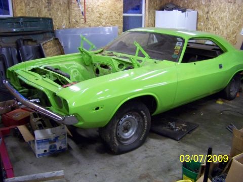 1974 Dodge Challenger - A bright green muscle car is parked inside a garage, with its hood propped open, revealing the engine bay.