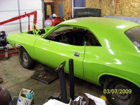 1974 Dodge Challenger - A lime green muscle car sits in a garage, undergoing restoration with the engine removed.