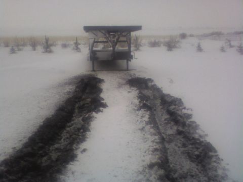 1992 Ford F-350 - A trailer sits in a snow-covered field, with tire tracks indicating recent passage.