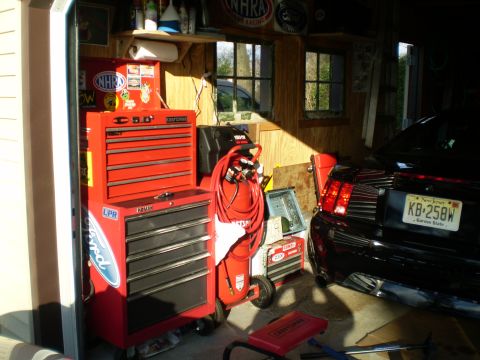 1981 Garelli Rally Sport - A black Ford Mustang is parked in a garage, with its rear visible next to a red toolbox and air compressor.