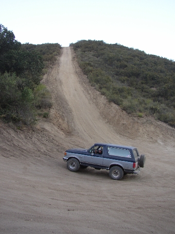 1989 Ford Bronco - A 1989 Ford Bronco navigates a steep, dusty trail on a hillside.