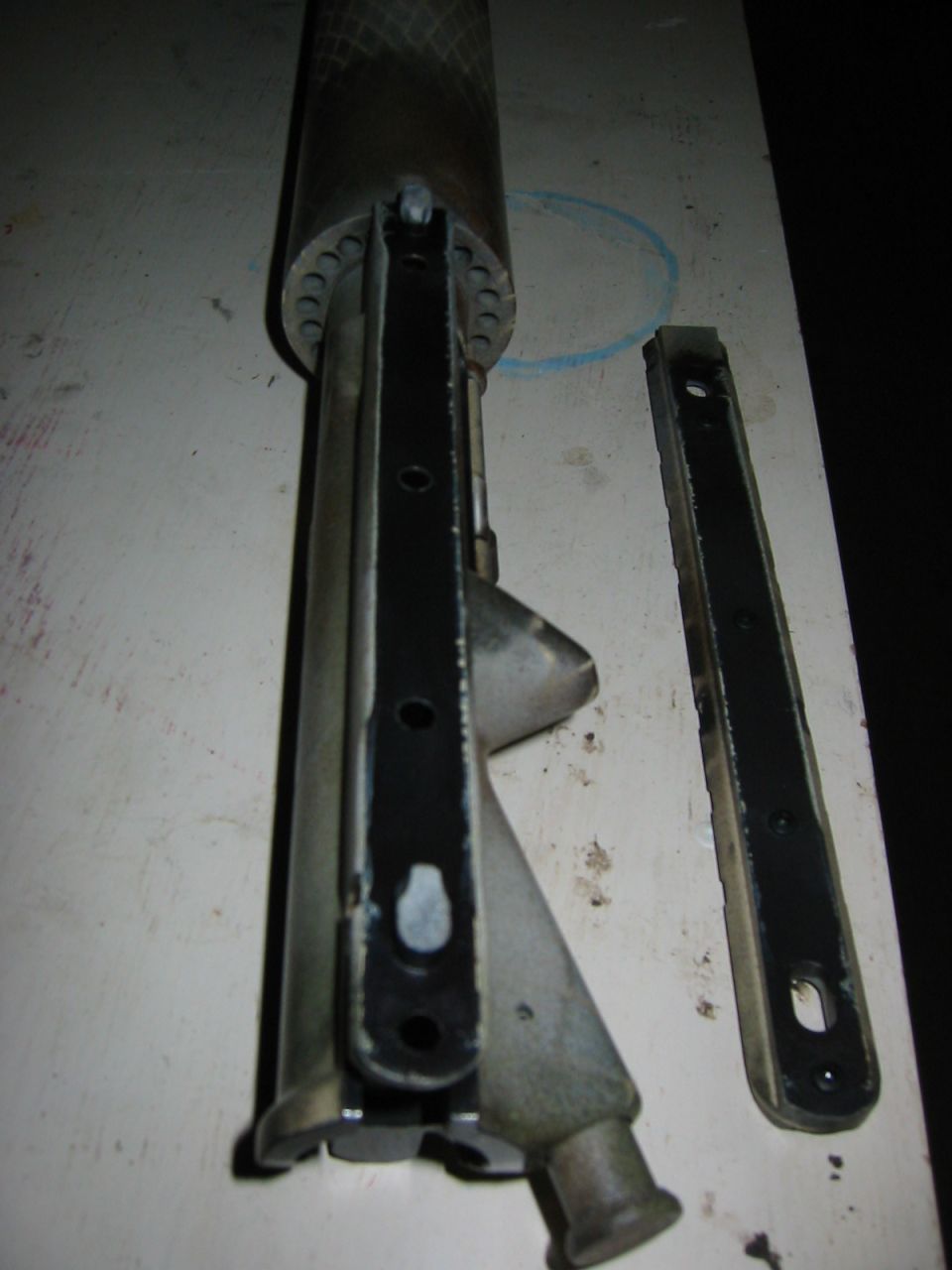 Close-up of a disassembled metal vehicle part with mounting holes