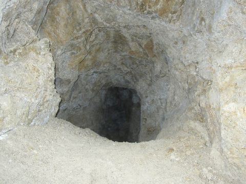 1989 Ford Bronco - The entrance to a cave or mine shaft is visible, with rough, natural rock formations and a sandy floor.