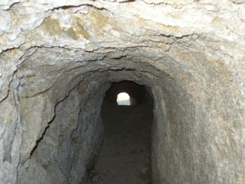 1989 Ford Bronco - Interior view of a rough-hewn cave tunnel leading to a distant opening.