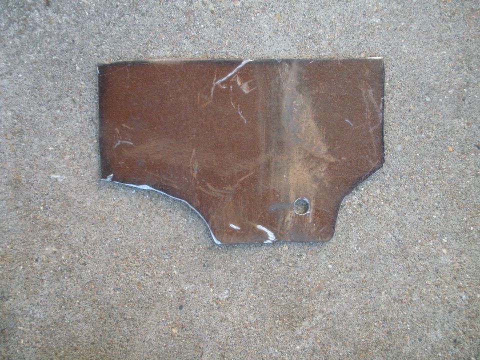 Brown metal bracket with a hole, lying on concrete