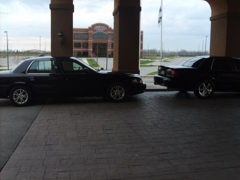 1993 Ford Crown Victoria - Two black sedans are parked side-by-side under a covered walkway.