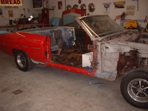 1970 Ford Torino - A red 1970 Ford Torino convertible is shown in a garage, stripped down for restoration with its doors removed.