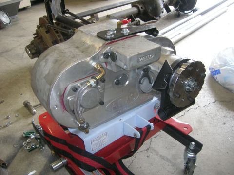 1996 Ford Bronco - Transfer case assembly with attached axles and driveshafts, mounted on a red stand.