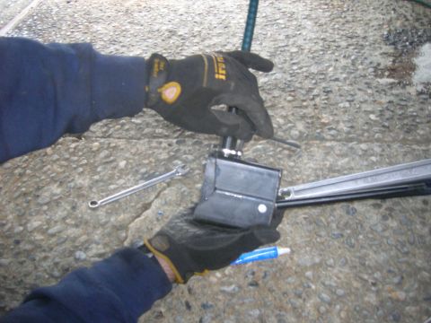 1996 Ford Bronco - A person is working on a mechanical part with tools on a concrete ground.