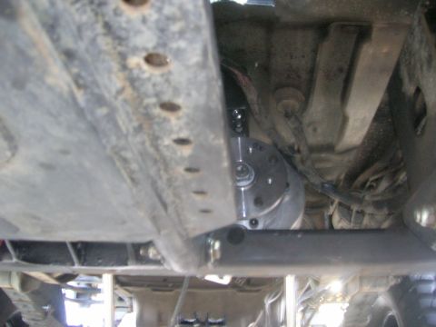 1996 Ford Bronco - A close-up shot reveals the complex undercarriage of a vehicle, focusing on mechanical parts and wiring.