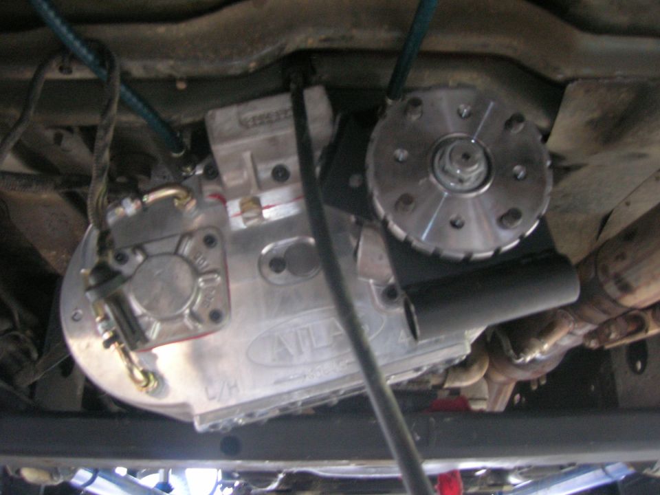 Underneath view of a vehicle's transfer case labeled 'ATLAS' and part of the exhaust system
