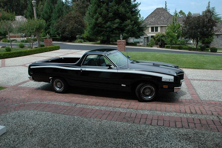 Black 1970 Ford Ranchero parked on a driveway with a house in the background