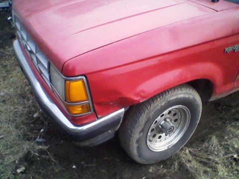 1992 Ford Ranger - This red pickup truck has a dent on its front fender, near the wheel.