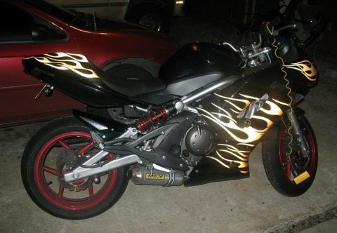 2008 Kawasaki Ninja R - A black motorcycle with prominent flame decals is parked next to a red car.