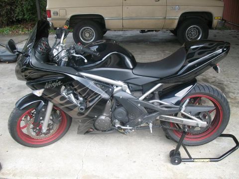 2008 Kawasaki Ninja R - Side view of a black 2008 Kawasaki Ninja R sportbike with flame decals and red wheel accents.