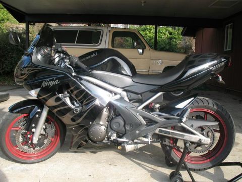 2008 Kawasaki Ninja R - A black Kawasaki Ninja motorcycle with flame decals and red rims is parked under a carport.
