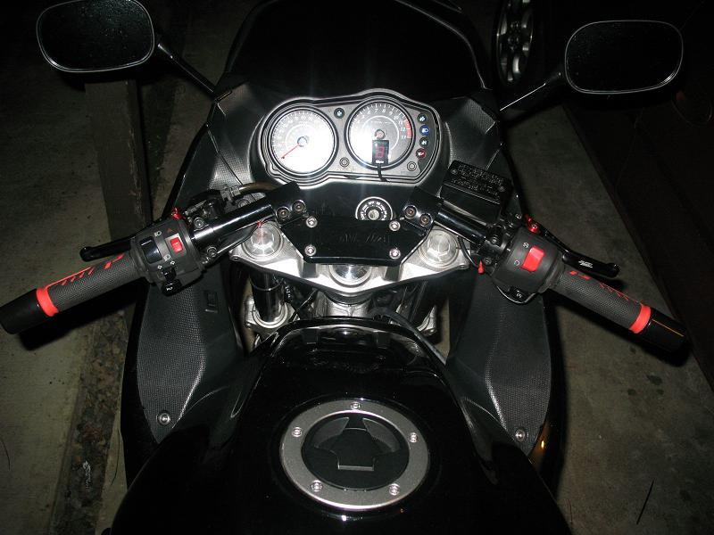 Black motorcycle handlebars with red accents and dual gauges