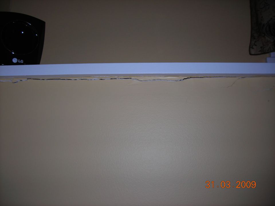 LG speaker on a shelf above a cracked wall