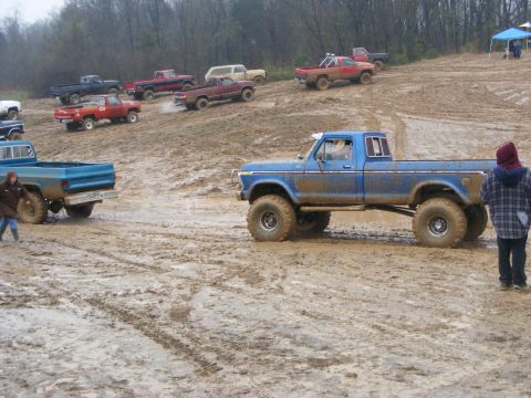 1979 Ford F-250 - Several pickup trucks, including a 1979 Ford F-250, navigate a muddy off-road course.