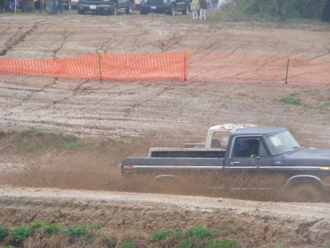 1979 Ford F-250 - A black 1979 Ford F-250 navigates a muddy track, with another vehicle partially visible in the background.