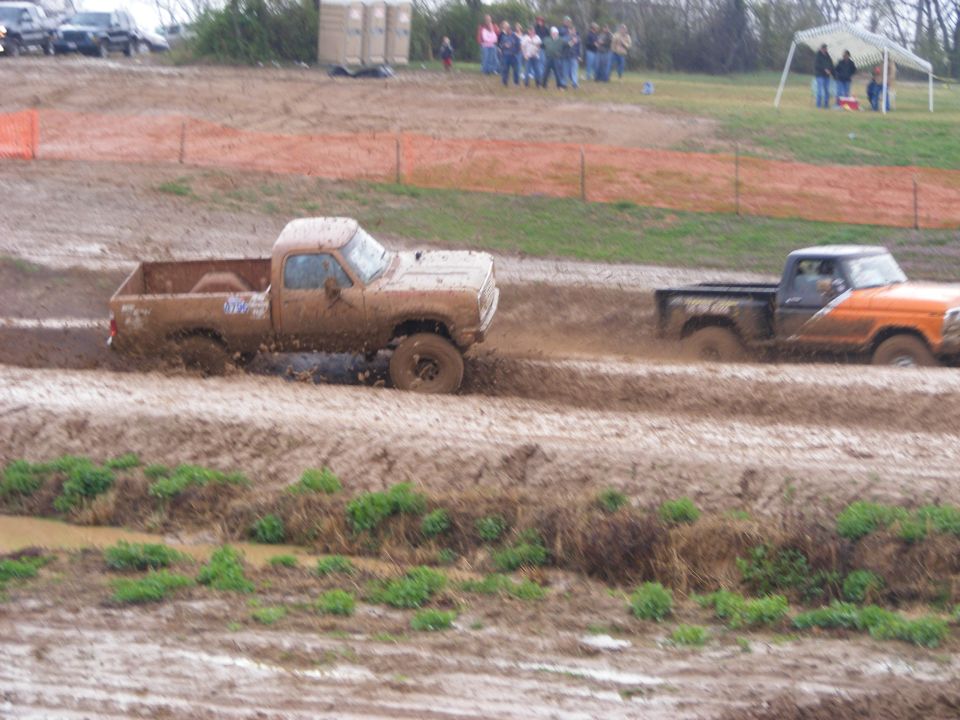 Two pickup trucks driving through mud.