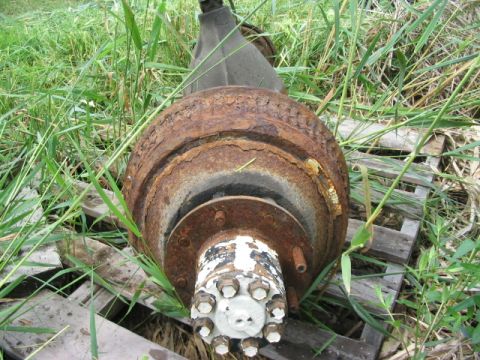 1986 Ford Bronco - Rusty brake drum and hub assembly, likely from a truck or large SUV, discarded outdoors.