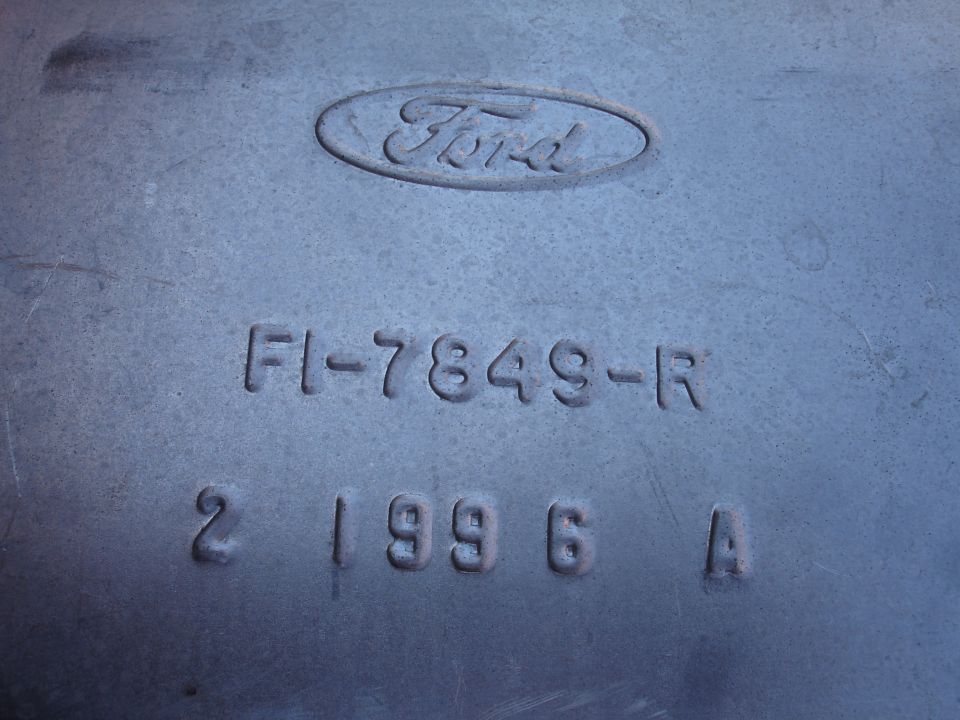 Close-up of a metal part with embossed Ford logo and part numbers.