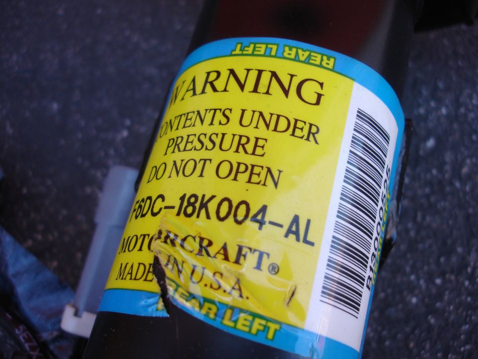 Yellow warning label on a black part with text and barcode.