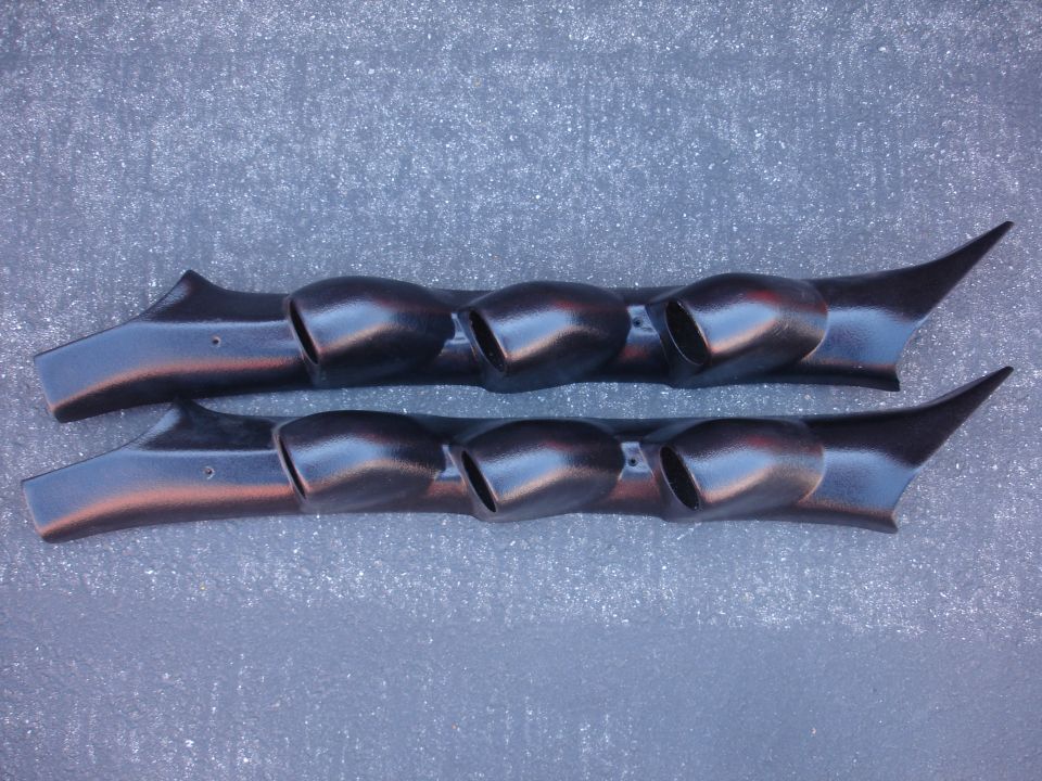 Two black triple gauge pods with pointed fronts on a gray surface.