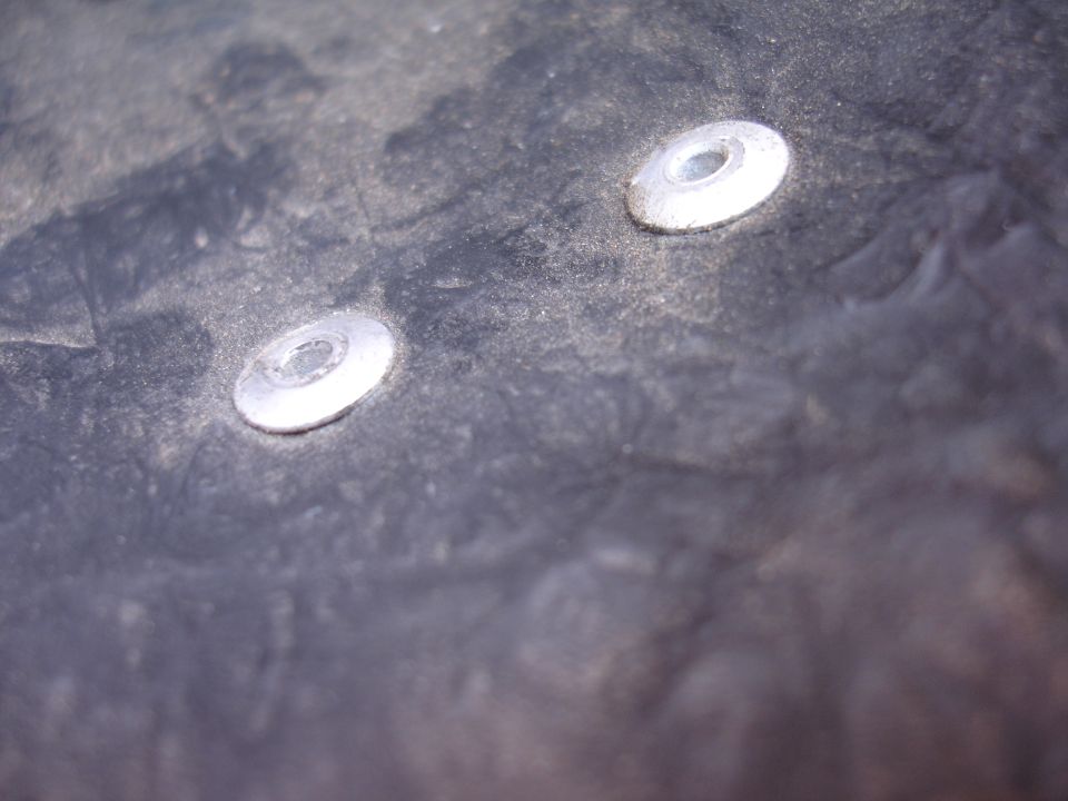 Two silver fasteners on a dark textured surface.