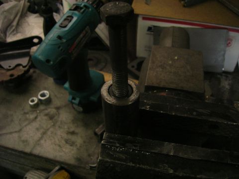 1996 Ford Bronco - A close-up shot of a bolt being held in a vise, with a cordless drill and two small metal rings visible in the background.