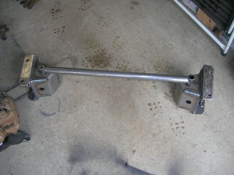 1996 Ford Bronco - A custom fabricated steel crossmember with mounting brackets is shown laid out on a concrete floor. The crossmember appears to be a suspens…