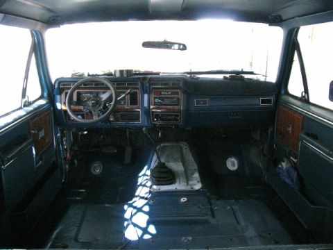 1984 Ford Bronco - Interior view of a blue Ford Bronco, showing the dashboard, steering wheel, and empty floor. The interior appears to be undergoing some wor…