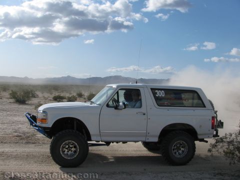 1990 Ford Bronco - Photo of race Bronco number 300 driving across desert terrain, not a technical document.
