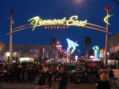 1990 Ford Bronco - illuminated Fremont East District neon archway spans a crowded Las Vegas street at night with off-road cars and pedestrians below.