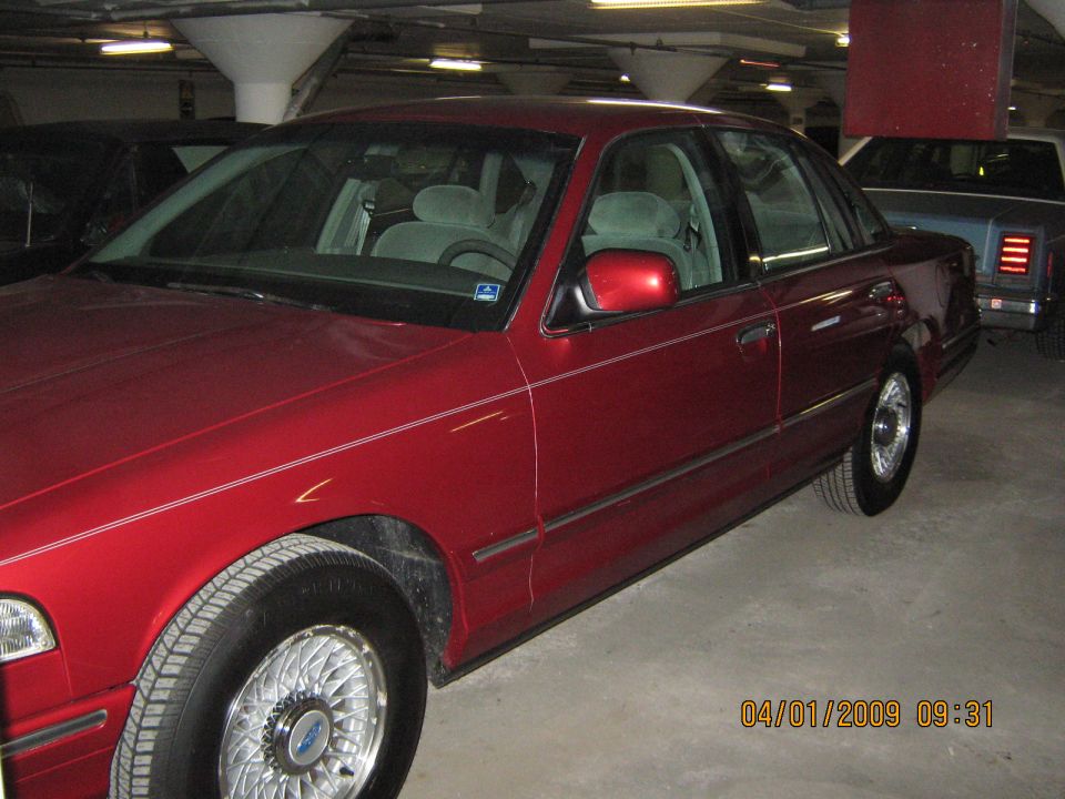 Red 1997 Ford Crown Victoria sedan, front passenger side view, in a parking garage