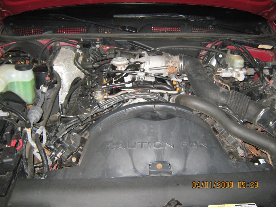 Red engine bay with visible "CAUTION FAN" text on a black shroud