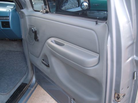 1994 Ford Bronco - Close-up of a vehicle's interior door panel, with another truck reflected in the side mirror.