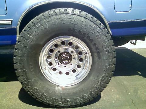 1996 Ford Bronco - Kumho Road Venture tire and chrome wheel on a blue vehicle.