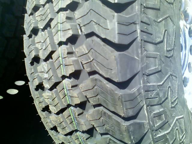 Close-up of a chunky off-road tire tread pattern. Shows the sidewall and part of the rim