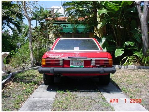 1994 Ford Bronco - A red Mercedes-Benz SL is parked in a driveway surrounded by lush greenery.