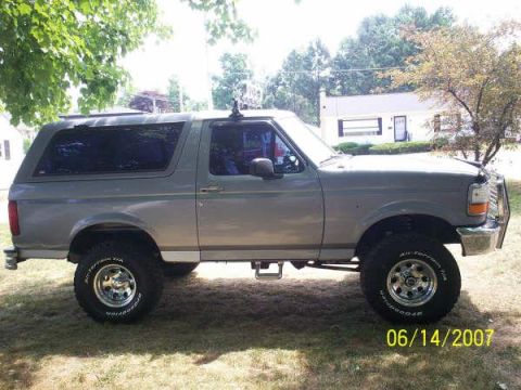 1994 Ford Bronco - A gray 1994 Ford Bronco is parked on a grassy lawn with a house in the background.