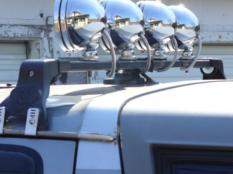 1994 Ford Bronco - Close-up of a roof rack equipped with four chrome spotlights, mounted on a silver SUV.